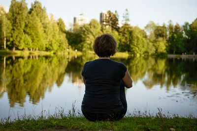 Woman sitting by the lake with her back