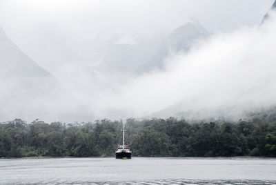 Scenic view of foggy mountains against sky,  milford sound, new zealand