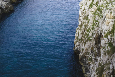 High angle view of rocky cliff by sea