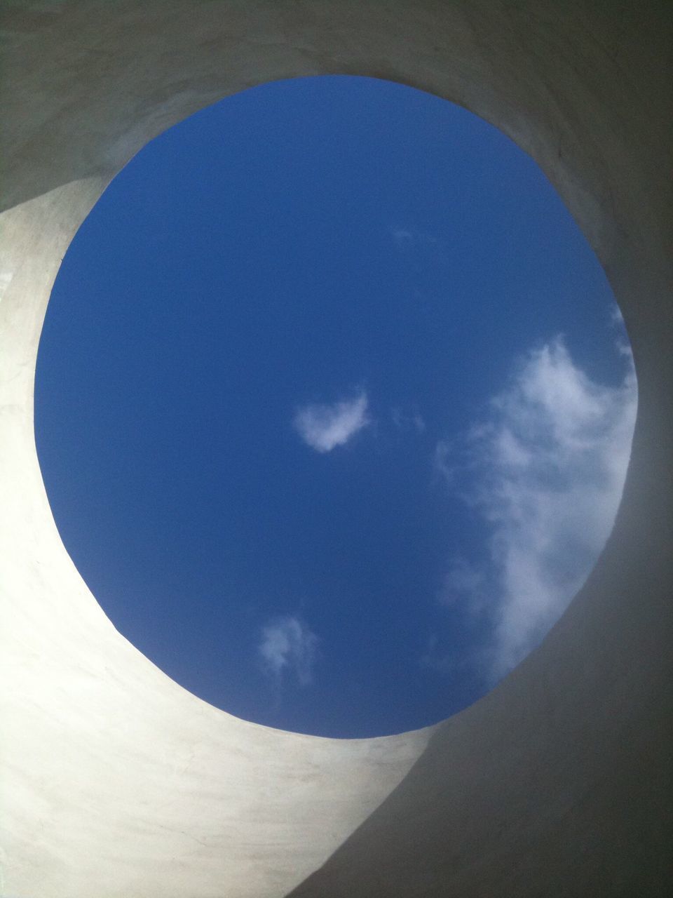 low angle view, circle, sky, built structure, architecture, geometric shape, indoors, arch, blue, no people, day, shape, directly below, cloud - sky, nature, cloud, tranquility, window, fish-eye lens