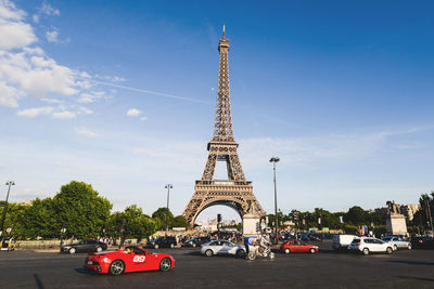 Cars on road with eiffel tower in background against sky