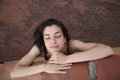 Portrait of woman against brick wall