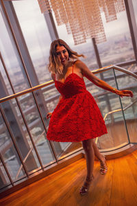 Full length of woman standing by railing against window at home