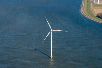 Wind turbines in sea against sky