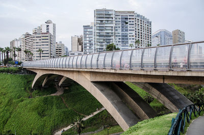 Arch bridge over river amidst buildings in city against sky
