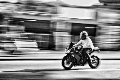 Rear view of man riding motor scooter on street