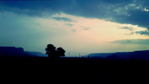 Silhouette trees on landscape against sky at sunset