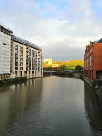 Buildings by river against sky in city