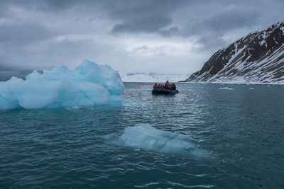 Group of people in zodiak boat explore iceberg in north polar sea ocean