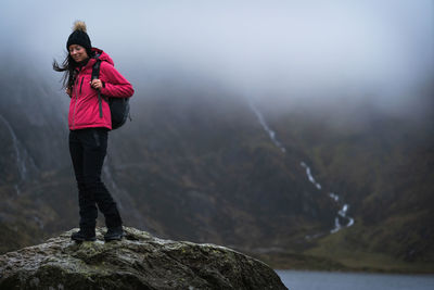 Man standing on rock against mountains during winter