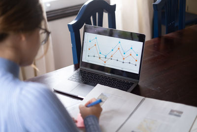 Midsection of woman using laptop on table