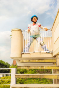 Low angle view of boy standing on steps against sky