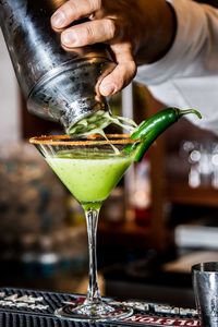 Cropped hand of person pouring drink in glass on table 