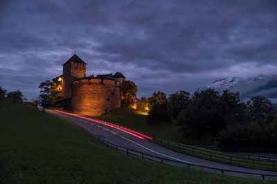 Road by building against sky at dusk