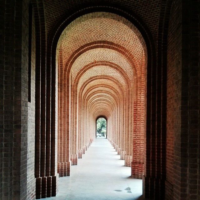 indoors, the way forward, arch, diminishing perspective, architecture, built structure, corridor, in a row, vanishing point, empty, ceiling, colonnade, architectural column, repetition, no people, building, day, architectural feature, history, long
