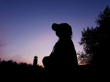 Silhouette woman standing by tree against sky during sunset