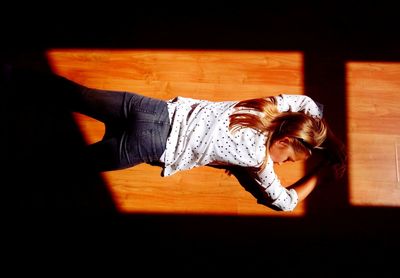 High angle view of woman lying on hardwood floor