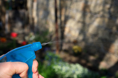 Cropped hand holding spray bottle outdoors