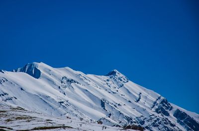 Scenic view of snow covered mountains against blue sky