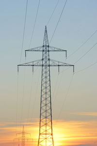 Low angle view of silhouette electricity pylon against sky during sunset