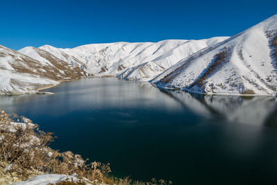 Beautiful mountain lake in winter. scenic view of snowcapped mountains and lake against blue sky.