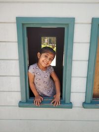 Portrait of smiling girl looking through window