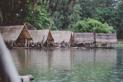 Wooden rafts with roofs moored in lake against trees