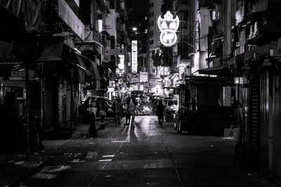 Illuminated street amidst buildings in city at night