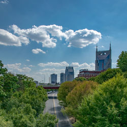 Road by buildings against sky in city