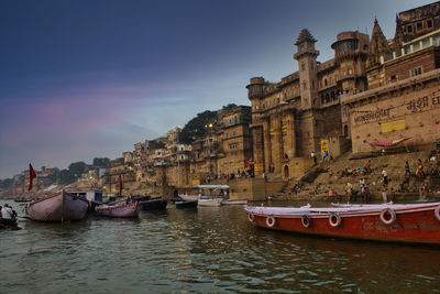 Boats moored on river by buildings in city