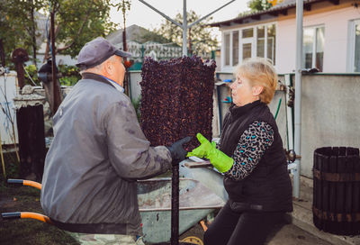 An elderly couple processes grapes for wine together.