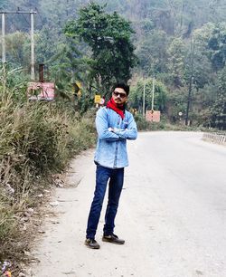 Full length portrait of young man standing on road