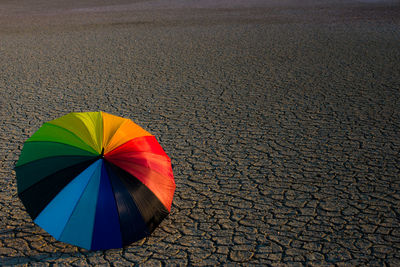 High angle view of multi colored umbrella on drought land