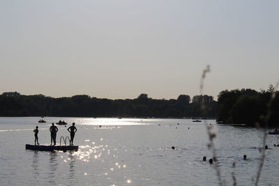 Silhouette people on raft at calm lake