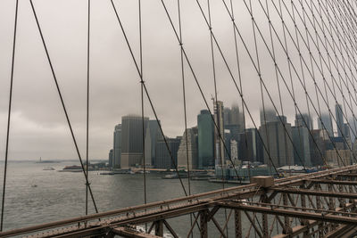 View of suspension bridge and buildings against sky