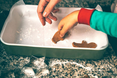 Moment unfolds in kitchen as a mom and son engage in tradition of preparing christmas gingerbread.