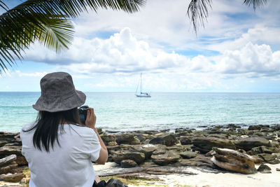 Rear view of woman on beach against sky