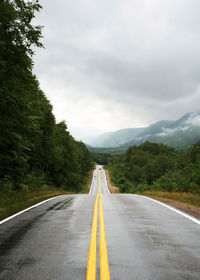 Road leading towards mountain against sky