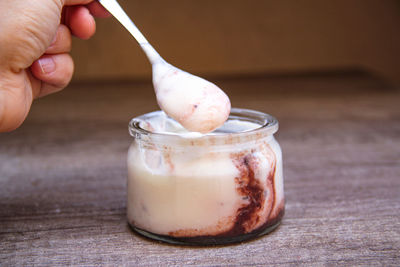 Close-up of hand holding ice cream in jar on table