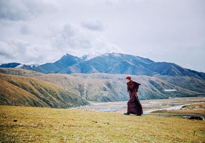 Woman standing on mountain road against sky