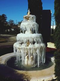 Fountain by trees against clear sky