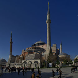 People at mosque against clear blue sky