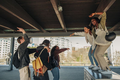 Carefree female friends performing dance at railroad station