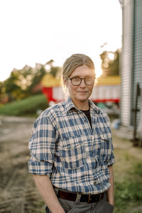 Smiling female farmer with hands in pockets standing at field