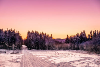 Snow covered land against clear sky during sunset