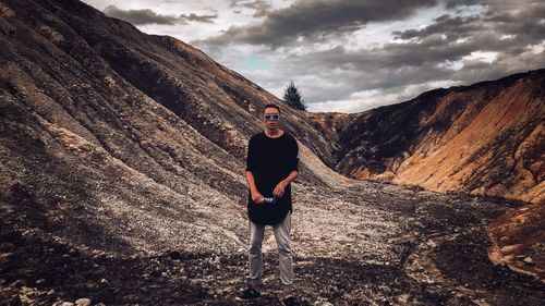 Portrait of man standing on land against mountains and sky