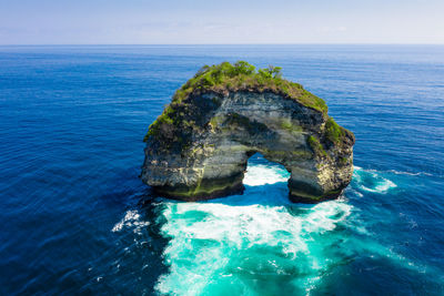 Rock formation in sea against blue sky