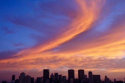 Buildings in city against sky at sunset