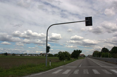 Road sign by street against sky