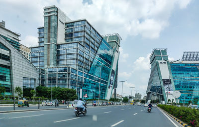 View of city street and modern buildings against sky